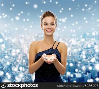 people, christmas, winter holidays and glamour concept - smiling woman in evening dress with diamond over snowy city background