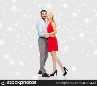 people, christmas, winter, love and holidays concept - happy couple hugging over snow background