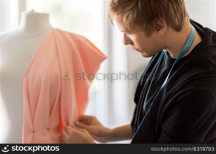people, clothing and tailoring concept - close up of fashion designer with dummy, cloth and pins making new dress at studio. fashion designer with dummy making dress at studio