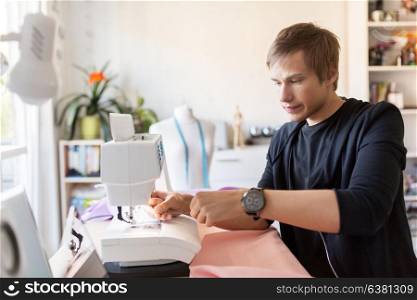 people, clothing and tailoring concept - fashion designer threading up sewing machine needle at studio. fashion designer with sewing machine at studio