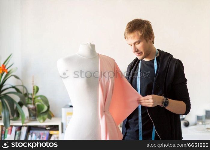 people, clothing and tailoring concept - fashion designer with dummy and cloth making new dress at studio. fashion designer with dummy making dress at studio