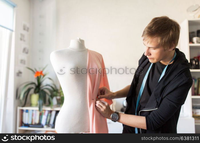 people, clothing and tailoring concept - fashion designer with dummy, cloth and pins making new dress at studio. fashion designer with dummy making dress at studio