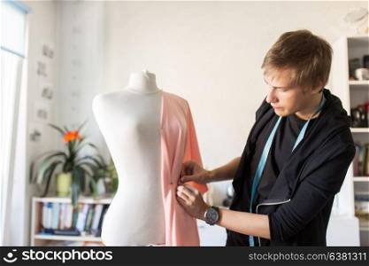 people, clothing and tailoring concept - fashion designer with dummy, cloth and pins making new dress at studio. fashion designer with dummy making dress at studio