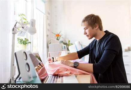 people, clothing and tailoring concept - fashion designer with sewing machine and cloth making new dress at studio. fashion designer with sewing machine working