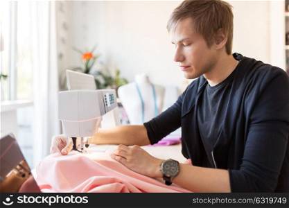 people, clothing and tailoring concept - fashion designer with sewing machine and cloth making new dress at studio. fashion designer with sewing machine working