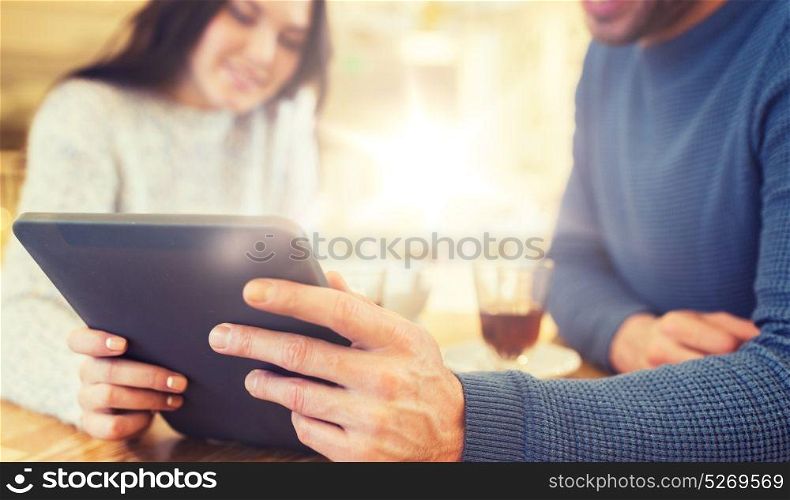 people, communication and dating concept - close up of happy couple with tablet pc computer at cafe or restaurant. happy couple with tablet pc drinking tea at cafe