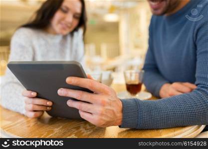 people, communication and dating concept - close up of happy couple with tablet pc computer at cafe or restaurant