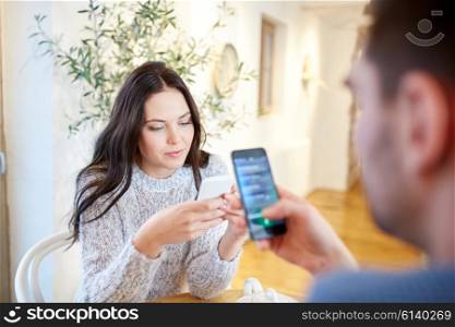 people, communication and dating concept - couple with smartphones at cafe or restaurant