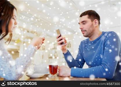 people, communication and dating concept - couple with smartphones drinking tea at cafe or restaurant