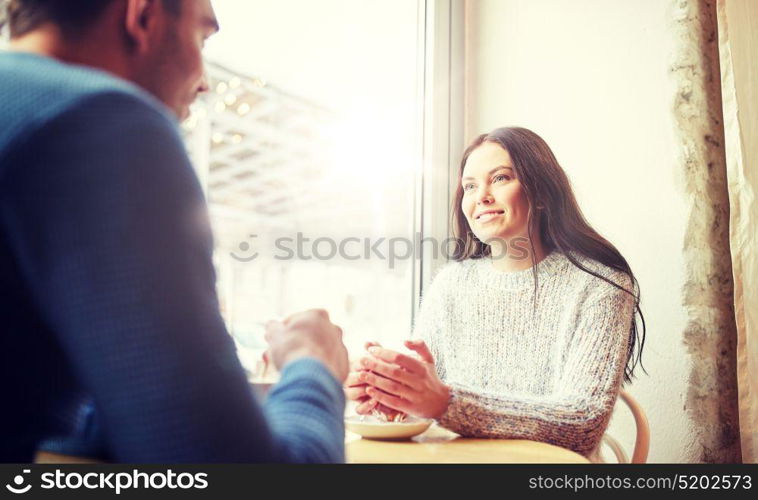 people, communication and dating concept - happy couple drinking tea and coffee at cafe. happy couple drinking tea and coffee at cafe