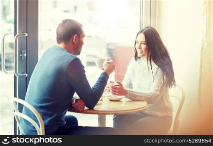 people, communication and dating concept - happy couple drinking tea and coffee at cafe. happy couple drinking tea and coffee at cafe