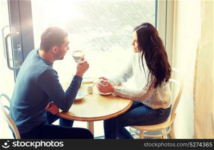 people, communication and dating concept - happy couple drinking tea and coffee at cafe. happy couple drinking tea and coffee at cafe