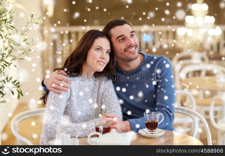 people, communication and dating concept - happy couple drinking tea and hugging at cafe or restaurant