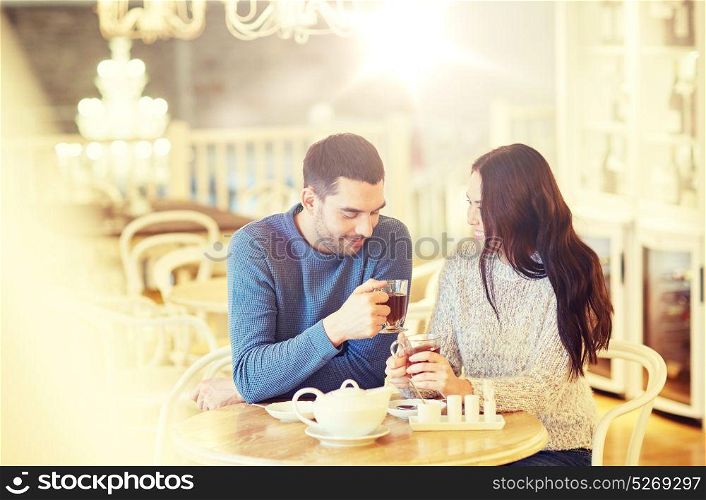 people, communication and dating concept - happy couple drinking tea at cafe or restaurant. happy couple drinking tea at cafe