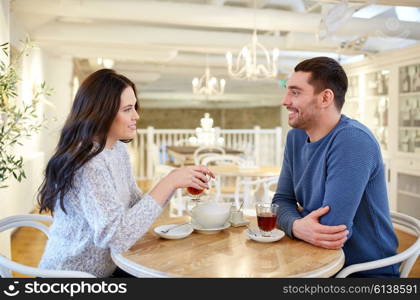 people, communication and dating concept - happy couple drinking tea at cafe or restaurant