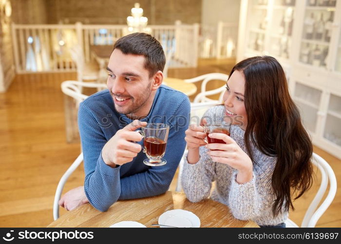 people, communication and dating concept - happy couple drinking tea at cafe or restaurant