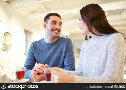 people, communication and dating concept - happy couple drinking tea at cafe or restaurant