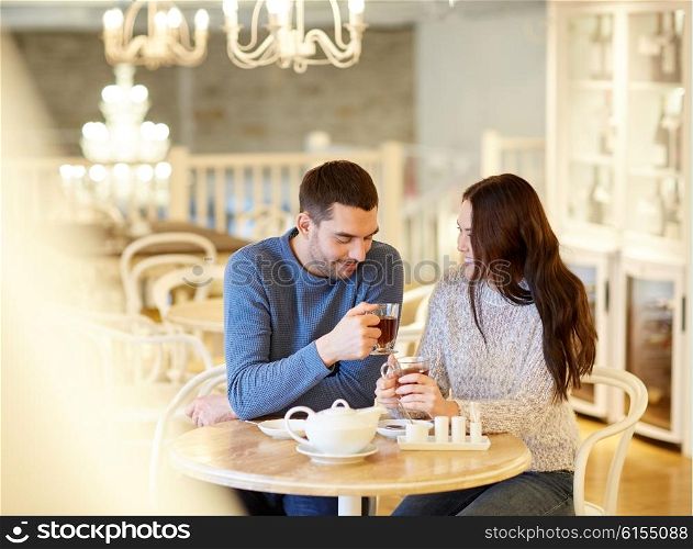 people, communication and dating concept - happy couple drinking tea at cafe or restaurant