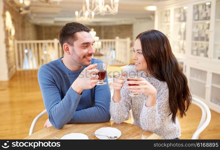 people, communication and dating concept - happy couple drinking tea at cafe or restaurant