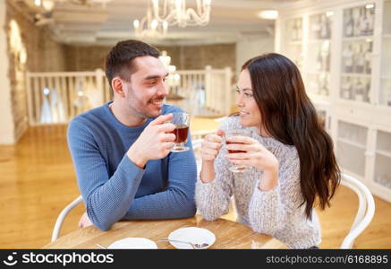 people, communication and dating concept - happy couple drinking tea at cafe or restaurant