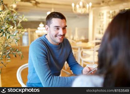 people, communication and dating concept - happy couple talking at cafe or restaurant
