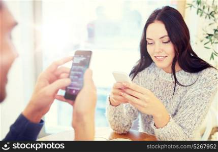 people, communication and dating concept - happy couple with smartphones at cafe or restaurant. happy couple with smartphones at cafe