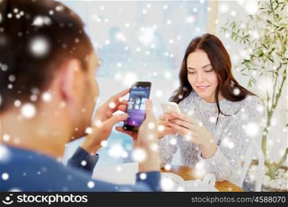people, communication and dating concept - happy couple with smartphones drinking tea at cafe or restaurant