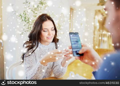people, communication and dating concept - happy couple with smartphones drinking tea at cafe or restaurant