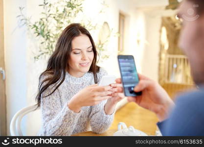 people, communication and dating concept - happy couple with smartphones drinking tea at cafe or restaurant