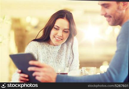people, communication and dating concept - happy couple with tablet pc computer at cafe or restaurant. happy couple with tablet pc drinking tea at cafe