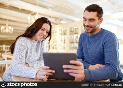 people, communication and dating concept - happy couple with tablet pc computer at cafe or restaurant