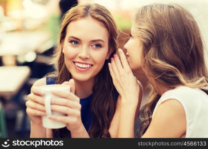 people communication and friendship concept - smiling young women drinking coffee or tea and gossiping at outdoor cafe. young women drinking coffee and talking at cafe