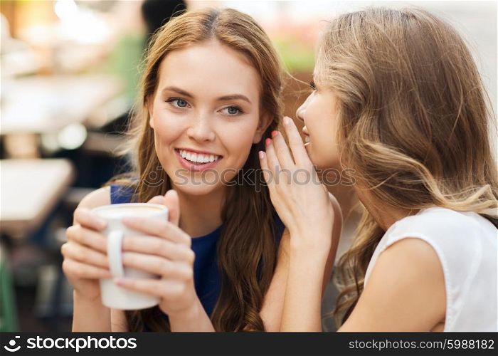 people communication and friendship concept - smiling young women drinking coffee or tea and gossiping at outdoor cafe. young women drinking coffee and talking at cafe