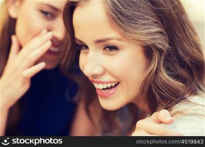 people, communication and friendship concept - smiling young women gossiping and whispering secrets