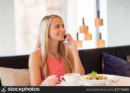 people, communication and leisure concept - happy woman drinking coffee at restaurant and calling on smartphone. woman with coffee calling smartphone at restaurant