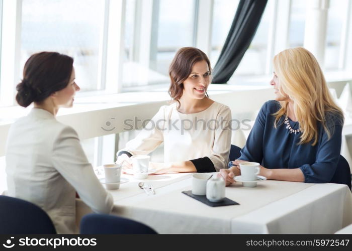 people, communication and lifestyle concept - happy women drinking coffee and talking at restaurant