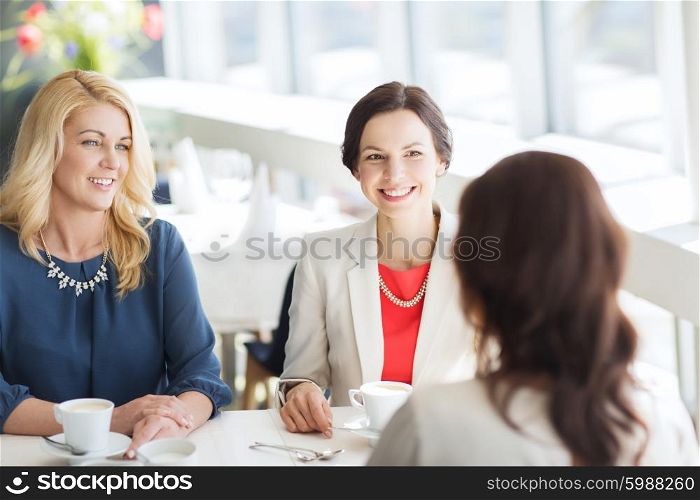 people, communication and lifestyle concept - happy women drinking coffee and talking at restaurant