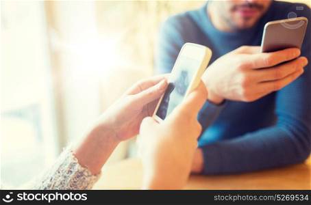 people, communication and technology concept - close up of couple with smartphones drinking tea at cafe or restaurant. close up of couple with smartphones at cafe