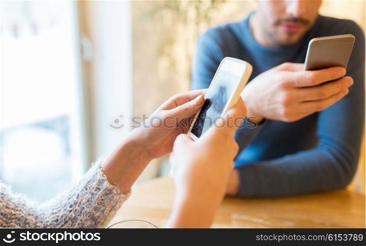 people, communication and technology concept - close up of couple with smartphones drinking tea at cafe or restaurant