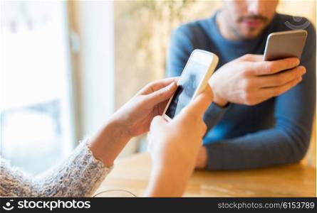 people, communication and technology concept - close up of couple with smartphones drinking tea at cafe or restaurant