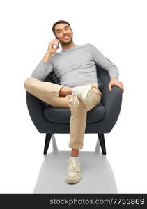 people, communication and technology concept - happy smiling man sitting in chair and calling on smartphone over white background. smiling man sitting in chair calling on smartphone