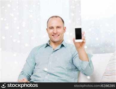people, communication, home and technology concept - smiling man showing blank smartphone screen at home