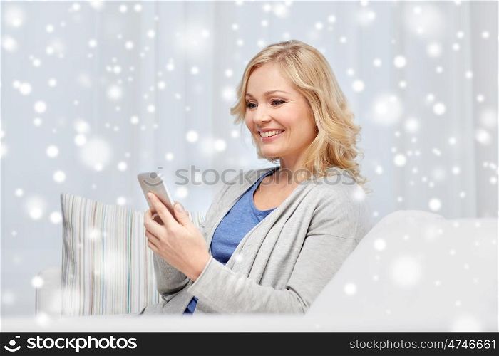 people, communication, technology and internet concept - smiling woman with smartphone texting at home over snow