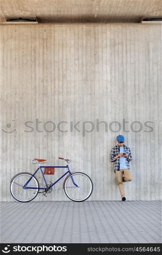 people, communication, technology and lifestyle - hipster man with smartphone, earphones and fixed gear bike listening to music on city street