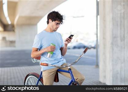 people, communication, technology and lifestyle - hipster man with smartphone, earphones and thermos cup on fixed gear bike listening to music on city street