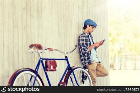 people, communication, technology and lifestyle - hipster man with smartphone, earphones and fixed gear bike listening to music on city street. man with smartphone, earphones and bicycle