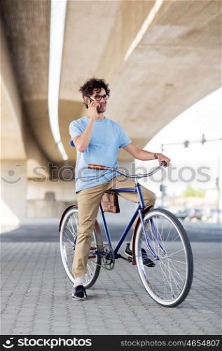 people, communication, technology, leisure and lifestyle - hipster man calling on smartphone and fixed gear bike on city street