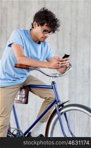 people, communication, technology, leisure and lifestyle - hipster man texting on smartphone with fixed gear bike on city street
