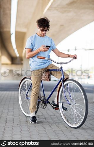 people, communication, technology, leisure and lifestyle - hipster man with smartphone and earphones on fixed gear bike listening to music on city street