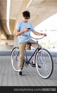 people, communication, technology, leisure and lifestyle - hipster man with smartphone and earphones on fixed gear bike listening to music on city street